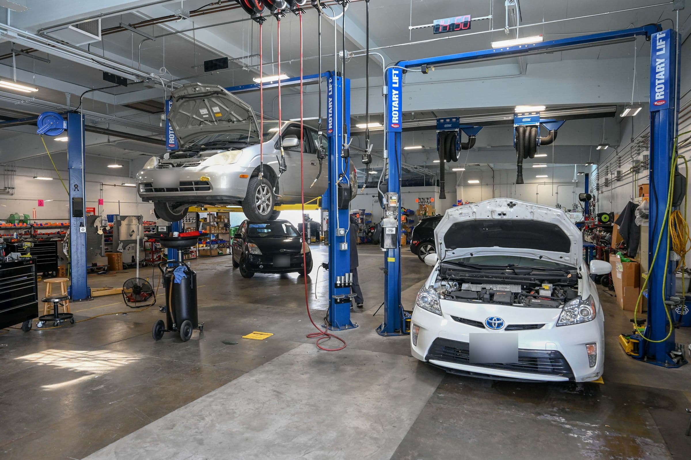 Two Rotary lifts, a Prius raised on one and another with its hood open on the floor