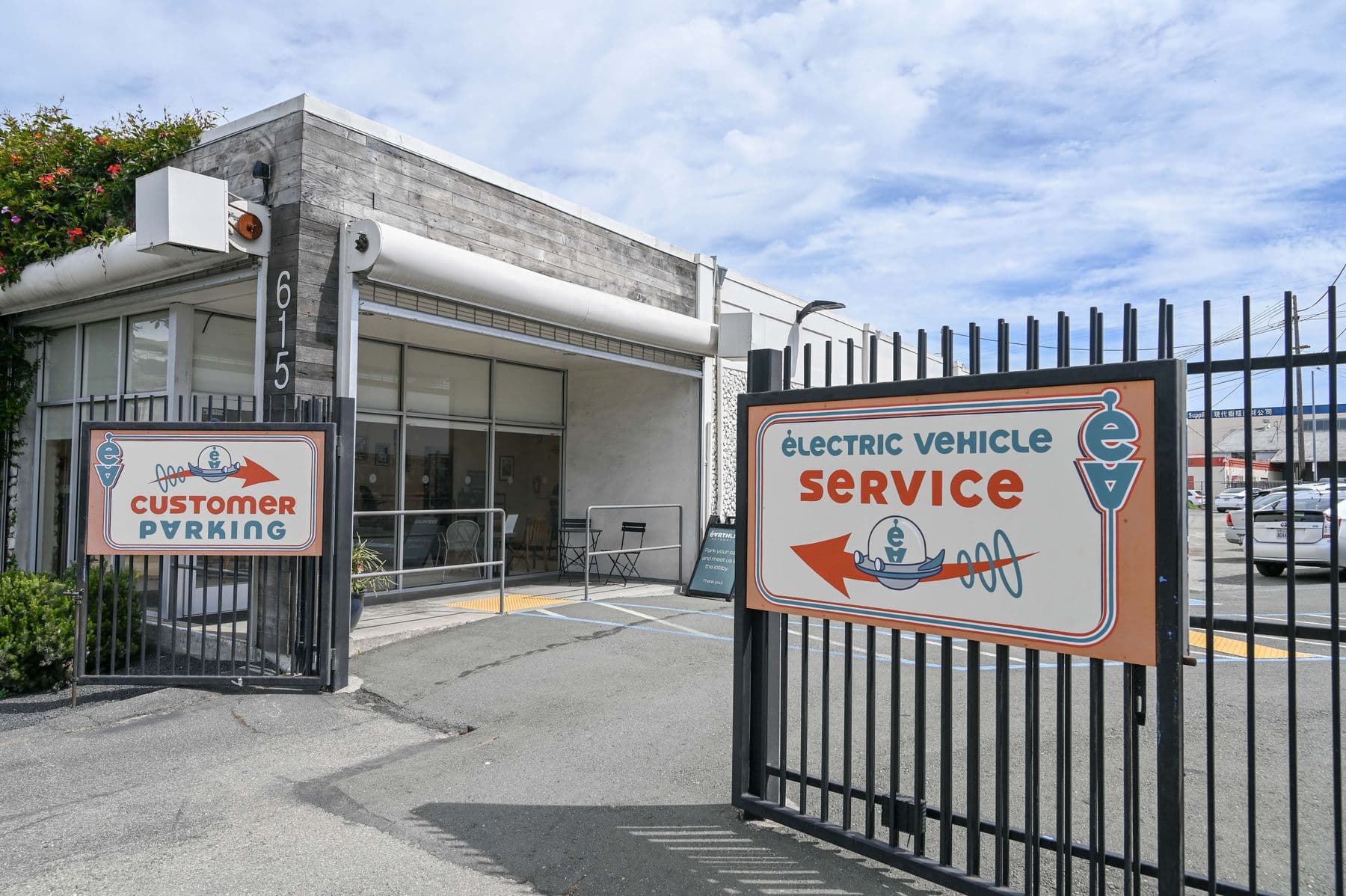 The front gate at 615 Bayshore with the customer parking sign and the Electric Vehicle Service sign