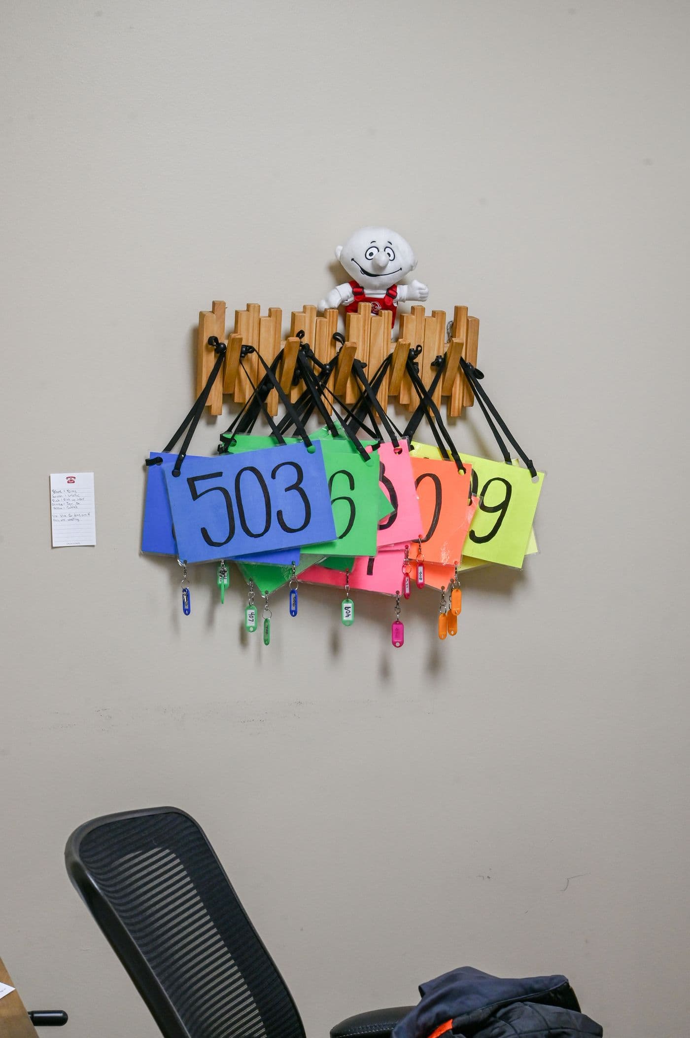 Bright numbered key tags hanging from a wooden rack on the office wall