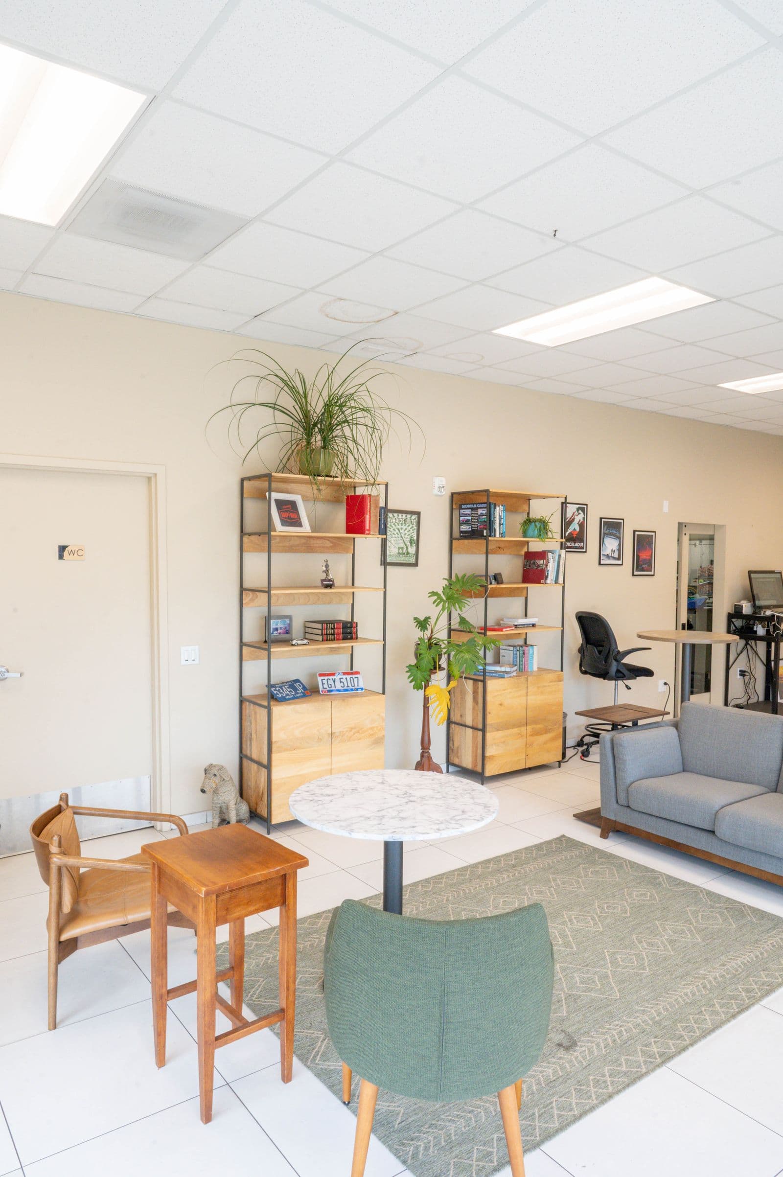 The Earthling lobby: a sofa, wooden shelves, plants and a green chair by the window