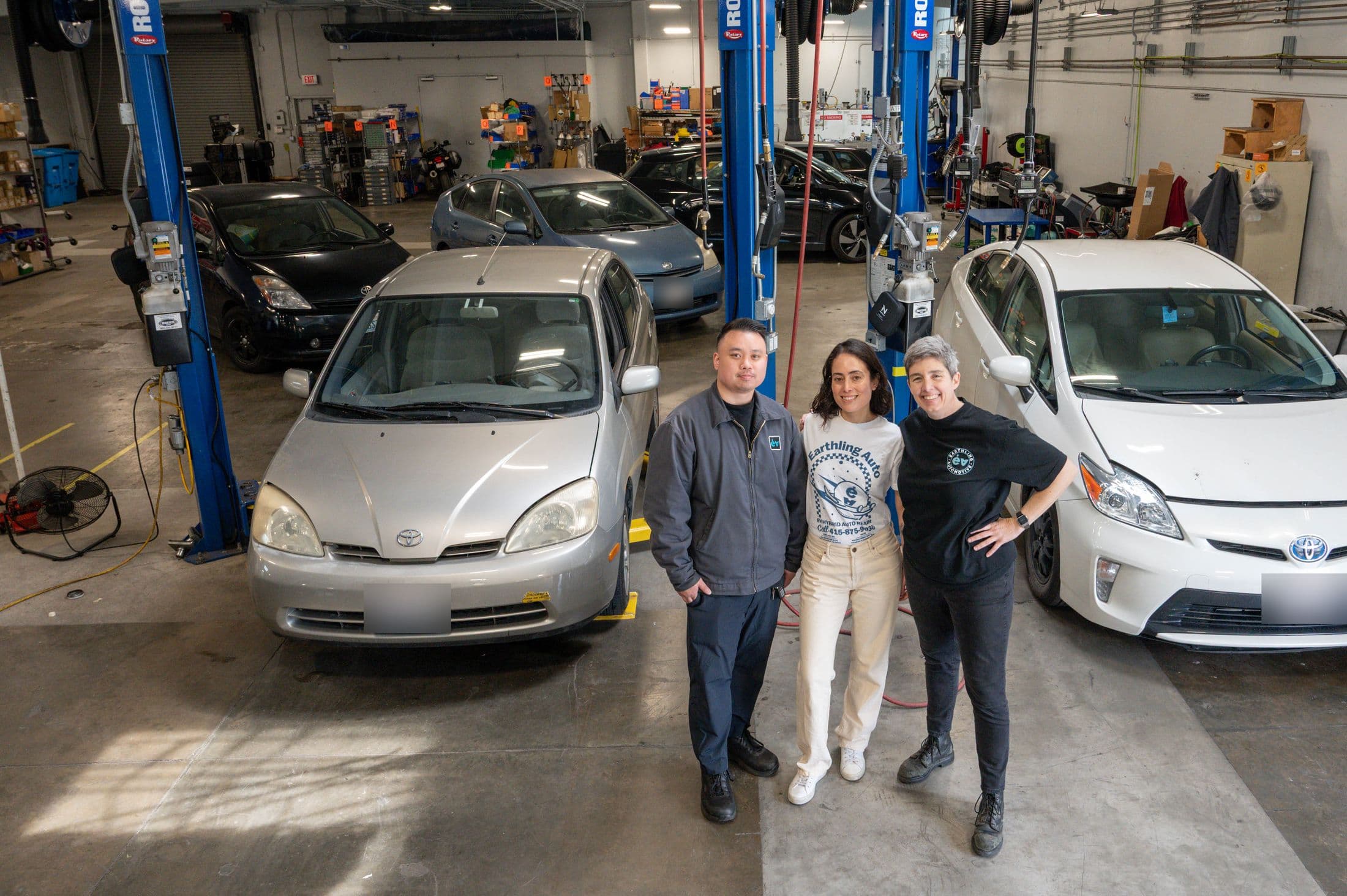 Three of the Earthling team between a gold first-generation Prius and a white third-generation Prius