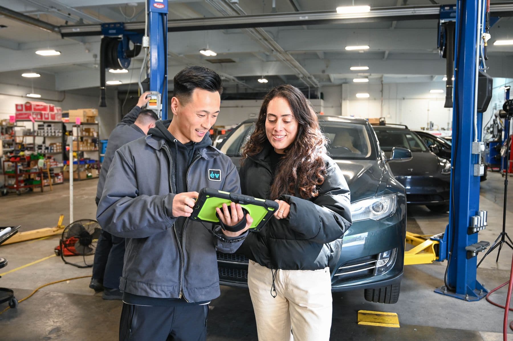 A technician and a customer reading the inspection on a tablet in front of her Model S