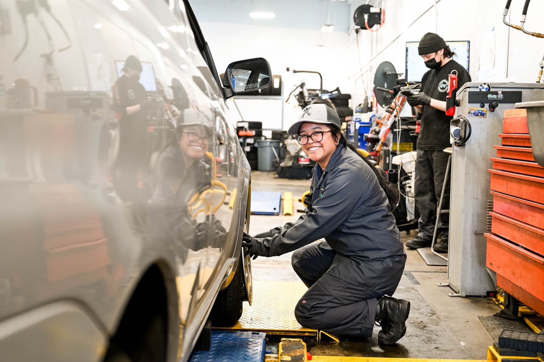 A technician smiling as she sets up a wheel on the alignment rack