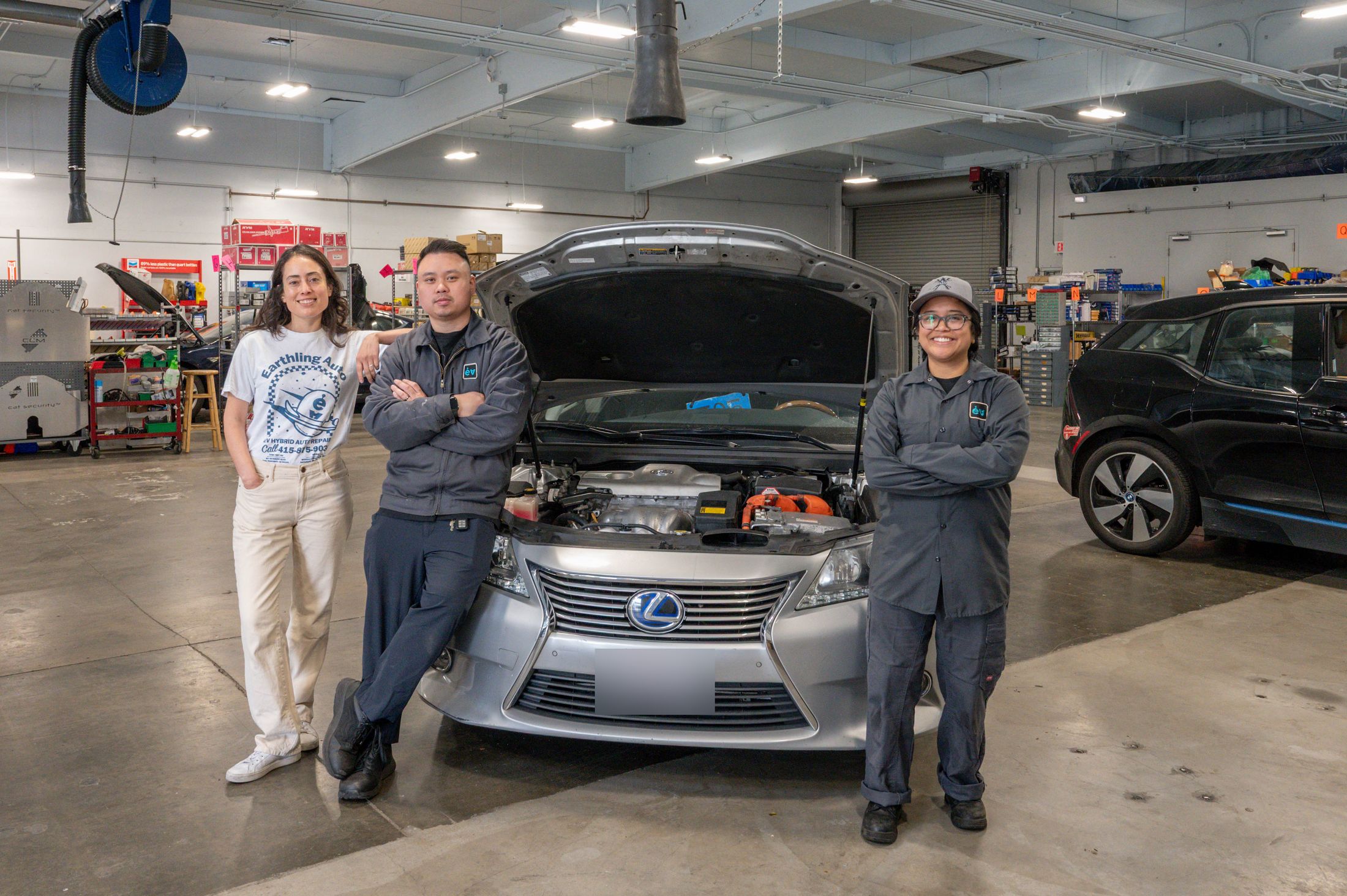 Three of the team around a Lexus hybrid with its hood up, a BMW i3 beside it