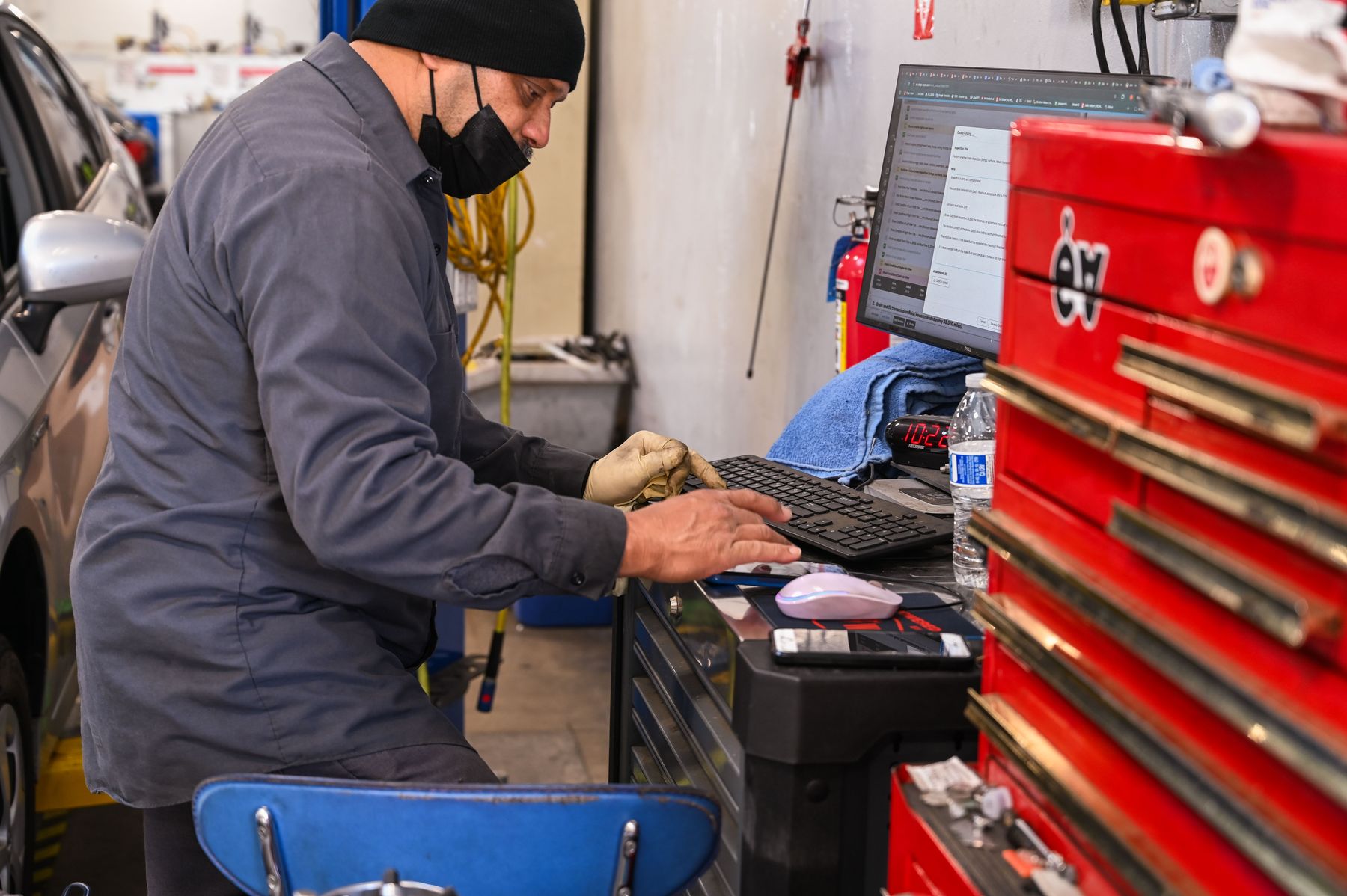 A technician in gloves typing up findings at the diagnostic station